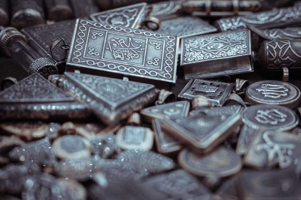 Close-up of antique silver amulets with ornate engravings in selective focus.